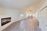 Located at 2180 Hawthorn Meadows in Howell, MI, this single-floor, 2-bedroom, 2-bathroom home offers a thoughtfully designed open-concept layout with impressive vaulted ceilings that lend a sense of spaciousness throughout. The expansive living and dining area is anchored by a sleek corner fireplace and flows seamlessly toward the kitchen, all finished with durable wood-look flooring and bathed in natural light from multiple windows with vertical blinds. A ceiling fan adds comfort to the main living space. The kitchen is well-appointed with white upper cabinetry, gray lower cabinets, light quartz countertops, stainless steel appliances including a range, microwave, and refrigerator, and a peninsula with a double undermount sink. Both bedrooms feature plush carpeting and natural light, with the primary bedroom offering soaring ceilings, a closet, and direct access to its en-suite bathroom. The bathrooms are elegantly finished with marble-look tile flooring; one features a glass-enclosed walk-in shower with full marble tile surround, while the other includes a clean white vanity with quartz countertop. Additional spaces include a laundry room, utility room, and multiple closets for ample storage throughout.