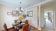 Located at 1 Drayson Way in Richmond, VA, this two-story, two-bedroom, three-bathroom home offers a well-organized layout across two floors. The main level features a living room, dining room, kitchen, and hallway, while the upper level houses the bedrooms and additional bathrooms.

The dining room is an elegant highlight, showcasing crown molding, a decorative column, wainscoting, warm hardwood flooring, a chandelier, and a large window that fills the space with natural light. The living room features a teal accent wall, plush carpeting, and expansive sliding glass doors that open to a private outdoor patio with garden views. The kitchen is equipped with warm maple cabinetry, stainless steel appliances, a double basin sink, and light tile flooring.

Upstairs, the spacious primary bedroom features carpeted floors, a closet, and a window with outdoor views. The second bedroom offers a cozy atmosphere with soft carpet, neutral tones, and warm lighting. The bathrooms include both a framed glass-door shower and a tiled soaking tub, providing practical and comfortable options. Throughout the home, neutral warm tones and classic detailing create a cohesive and inviting ambiance.