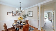 Located at 1 Drayson Way in Richmond, VA, this two-story, two-bedroom, three-bathroom home offers a well-organized layout across two floors. The main level features a living room, dining room, kitchen, and hallway, while the upper level houses the bedrooms and additional bathrooms.

The dining room is an elegant highlight, showcasing crown molding, a decorative column, wainscoting, warm hardwood flooring, a chandelier, and a large window that fills the space with natural light. The living room features a teal accent wall, plush carpeting, and expansive sliding glass doors that open to a private outdoor patio with garden views. The kitchen is equipped with warm maple cabinetry, stainless steel appliances, a double basin sink, and light tile flooring.

Upstairs, the spacious primary bedroom features carpeted floors, a closet, and a window with outdoor views. The second bedroom offers a cozy atmosphere with soft carpet, neutral tones, and warm lighting. The bathrooms include both a framed glass-door shower and a tiled soaking tub, providing practical and comfortable options. Throughout the home, neutral warm tones and classic detailing create a cohesive and inviting ambiance.