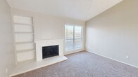 This well-appointed 2-bedroom, 3-bathroom single-floor residence offers a thoughtfully designed layout that maximizes functionality and comfort. The living room serves as the heart of the home, highlighted by dramatic vaulted ceilings, a ceiling fan, a white brick fireplace flanked by built-in shelving, and a large window that invites an abundance of natural light. Plush carpeting runs throughout the main living areas, while wood-look flooring transitions through the entryway and kitchen.

The kitchen is efficiently designed with white appliances including a refrigerator and electric range, complemented by granite-style countertops, cabinetry, and a dedicated pantry for additional storage. The open-concept flow connects the kitchen to the dining and living areas seamlessly.

The primary bedroom offers generous proportions and features a window for natural light, while bedrooms are accompanied by well-sized walk-in closets outfitted with built-in shelving and hanging rods. Three full bathrooms include tub-shower combinations with white tile surrounds.

Additional features include a dedicated laundry area, a hallway for smooth circulation, and a sliding glass door providing outdoor access. The neutral color palette throughout creates a clean, move-in-ready atmosphere.
