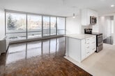 Located at 20 N Shore Blvd W in Burlington, Ontario, this 2-bedroom, 1-bathroom unit offers a well-organized single-floor layout with a clean, modern aesthetic throughout. The open-concept kitchen and living area serves as the heart of the space, where a central island with granite countertops anchors the kitchen. White shaker-style cabinetry extends to the ceiling, providing ample storage, while stainless steel appliances — including a French door refrigerator, electric range with microwave, and dishwasher — complete the functional setup. Recessed and pendant lighting adds warmth to the kitchen area.

The living room is generously proportioned and defined by gleaming parquet hardwood flooring and expansive floor-to-ceiling sliding glass windows that invite abundant natural light and offer outdoor views. A balcony is accessible from the living area.

Both bedrooms feature the same warm parquet flooring and neutral white walls, with the primary bedroom offering a comfortable footprint. A hallway connects the rooms and leads to the full bathroom, which is finished with a granite-topped white vanity, a large mirror, tile flooring, and a glass-enclosed walk-in shower. A dedicated closet provides additional storage within the unit.