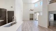 Located at 1001 East Playa Del Norte Drive in Tempe, Arizona, this two-story, 2-bedroom, 2-bathroom home offers a well-designed layout spread across two floors. The main level is the larger of the two, encompassing an open-concept living and kitchen area highlighted by dramatically soaring ceilings with clerestory windows that flood the space with natural light. A ceiling fan anchors the living area, which also features a sleek built-in fireplace — a standout focal point. The kitchen is equipped with dark cabinetry, stainless steel appliances including a refrigerator, microwave, and range, and a white countertop peninsula with an integrated sink. Light-toned wood-look flooring runs throughout both floors, contributing to a clean, contemporary aesthetic. A staircase with a modern metal railing connects the main level to the upper floor, which offers a more intimate setting. Both bedrooms are comfortably sized, featuring ceiling fans and ample natural light — one with sliding mirror closet doors and another with a large window dressed with vertical blinds. The two bathrooms are identically appointed with tub/shower combos, white tile surrounds, dark-toned vanities, and white countertops. The overall ambiance is modern, bright, and minimalist.