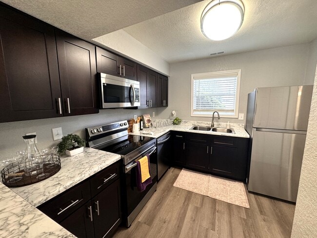 Cocina totalmente equipada con electrodomésticos de acero inoxidable e iluminación natural. - Devon Pointe Apartments and Townhomes