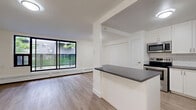 Located at 1320 Danforth Road in Toronto's Scarborough neighbourhood, this one-bedroom, one-bathroom unit offers a well-organized layout spread across a single floor. The open-concept living and kitchen area serves as the heart of the home, featuring light wood-tone laminate flooring that runs throughout the unit, creating a warm and cohesive aesthetic.

The kitchen is thoughtfully designed with white shaker-style cabinetry, dark countertops, a classic white subway tile backsplash, and a full suite of stainless steel appliances including a refrigerator, stove, microwave, and dishwasher. A peninsula provides additional counter space and casual seating potential. The living area is bright and airy, highlighted by large sliding glass doors that flood the room with natural light and offer views of the surrounding greenery.

The bedroom is a comfortable, well-proportioned room with a window overlooking lush trees, a built-in closet with double doors, and baseboard heating. The bathroom features clean white subway tile surrounding a full soaker tub and shower combination, complemented by a pedestal sink and toilet. A hallway connects the rooms efficiently, completing this functional and modern unit.