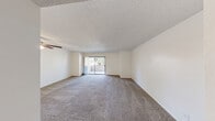 Located at 4255 S Tamarus St in Las Vegas, NV, this one-bedroom, one-bathroom unit offers a well-organized single-level layout designed for comfortable everyday living. The open living room is generously proportioned, featuring plush carpeting, neutral walls, a ceiling fan with light fixture, a textured ceiling, and a sliding glass door that leads to a private balcony with views of surrounding greenery, filling the space with natural light. The kitchen is positioned adjacent to the living area and features warm wood-toned cabinetry, a white electric range, a full-size refrigerator, a countertop with a pass-through bar, and a track lighting fixture overhead. The bedroom is a well-sized retreat with carpet flooring, a large sliding window that invites ample natural light, and access to two closets, providing generous storage options. The full bathroom includes a tub/shower combination, a toilet, wood-look tile flooring, and a small window for natural ventilation. Consistent neutral tones and textured ceilings flow throughout the unit, creating a clean and cohesive aesthetic. The layout is efficient and practical, making excellent use of the available space throughout.