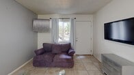 Located at 1950 North 43rd Avenue in Phoenix, Arizona, this single-floor unit offers a well-organized layout comprising one bedroom, a living room, a kitchen, and a closet. The space makes efficient use of its footprint, with each room serving a clear purpose.

The living room features light tile flooring, a textured ceiling, and a window with curtains that allow natural light to filter in, creating a bright and welcoming entry point to the unit. The room provides enough space for comfortable seating and entertainment essentials.

The kitchen is equipped with white cabinetry extending to the ceiling for ample storage, a white electric range, a double-basin sink with granite-style countertops, and a full-size refrigerator. Light tile flooring continues throughout, and the layout accommodates a dining table, making it a combined kitchen and dining area ideal for everyday use.

The bedroom is a comfortable, well-proportioned room featuring tile flooring, a textured ceiling, and a window with vertical blinds and curtains that provide natural light and privacy. The room offers sufficient space for a full-size bed and additional furniture such as a dresser with mirror. A dedicated closet provides convenient storage.

Overall, the unit presents a practical and functional living space with a neutral color palette and consistent finishes throughout, suited for single occupancy in a central Phoenix location.