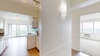 This thoughtfully designed two-bedroom residence spans a single floor and offers a functional, open layout with clean, modern finishes throughout. The entrance leads into a bright interior where light wood-tone flooring flows through the main living areas, creating a cohesive and airy feel.

The galley-style kitchen is a standout feature, equipped with white cabinetry, granite countertops, a mosaic tile backsplash, and track lighting overhead. Appliances including a range, microwave, and dishwasher are included, and the kitchen opens toward a sliding glass door that frames sweeping outdoor views and provides access to a balcony area.

The spacious living room continues the light hardwood flooring and features large floor-to-ceiling windows that invite abundant natural light and offer expansive panoramic views of the surrounding landscape. The room opens fluidly from the kitchen, making it ideal for entertaining.

The generously sized primary bedroom is carpeted for comfort and features wide windows with the same impressive views, built-in louvered closet doors providing ample storage, and a wall-unit air conditioner. The second bedroom mirrors this design with light hardwood flooring, louvered closet access, and connectivity to the main hallway. An in-unit washer and dryer are also present, adding everyday convenience to this well-rounded residence.