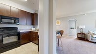 Located at 285 Park Ave in Pooler, Georgia, this single-story residence offers a well-designed, open-concept layout that connects the main living areas seamlessly. The kitchen is outfitted with rich dark wood cabinetry, granite-style countertops, tile flooring, and stainless steel appliances including a full-size refrigerator. A structural column and breakfast bar create a natural division between the kitchen and the adjacent dining nook, which features crown molding and carpeted flooring. The living room is generously proportioned, finished with plush carpet, crown molding, and a ceiling fan with light. A large sliding glass door floods the space with natural light and provides direct access to an outdoor patio with views of the surrounding area. An elegant arched passage connects the entryway to the main living space, adding an architectural detail that enhances the overall flow. The bedrooms are comfortable and well-lit, each featuring large windows with blinds and drapes, soft carpet, and neutral wall tones. The bathroom includes a wide vanity with dark wood cabinetry, a granite-style countertop, a large mirror with overhead lighting, and tile flooring. A laundry area is also present within the unit.