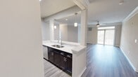 Located at 3100 Ashley Town Center in Charleston, SC, this single-story residence offers a well-appointed, open-concept layout designed for comfortable everyday living. The interior is finished with wood-look plank flooring throughout the main living areas, complemented by neutral-toned walls and crisp white crown molding that lend a clean, cohesive aesthetic.

The kitchen is a functional centerpiece, featuring rich dark cabinetry, white quartz countertops, a subway tile backsplash, and a full suite of stainless steel appliances including a refrigerator, range, microwave, and dishwasher. Pendant lighting above the peninsula-style counter enhances both task lighting and visual appeal. The kitchen opens directly to the main living area, which benefits from natural light and sliding glass door access to an outdoor space.

Bedrooms are carpeted for comfort, each equipped with a ceiling fan and natural window views. The primary bedroom includes a spacious walk-in closet with built-in shelving. The en-suite primary bathroom features a dual-sink vanity with dark cabinetry, a soaking tub, and wood-look tile flooring. A secondary half-bath provides added convenience for guests. A smart thermostat is also included, adding a modern, practical touch throughout the home.