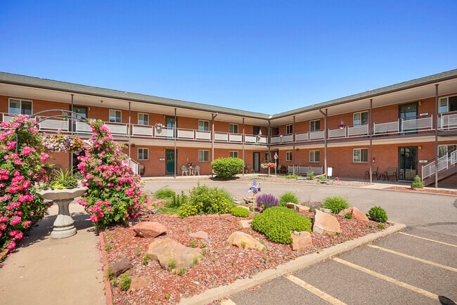 Charming apartment complex with well-maintained gardens and blooming flowers under a clear blue sky. - Lakeview Apartments
