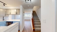 Located at 1401 Eland Downe in Phoenixville, PA, this two-story, two-bedroom, two-bathroom home offers a clean, modern aesthetic with thoughtful finishes throughout. The main floor opens into a bright living room with warm hardwood-style flooring and a front entry door flanked by natural light-inviting windows. Adjacent to the living area, the updated kitchen is a standout feature, showcasing gray shaker-style cabinetry, crisp white quartz countertops, stainless steel appliances including a refrigerator, range, and microwave, and a peninsula that adds extra prep and serving space. Track lighting overhead enhances the functional layout. A carpeted staircase with a warm wood banister leads to the upper floor, where both bedrooms are located. The generously sized primary bedroom features plush carpeting and dual windows that fill the room with natural light. The second bedroom, also carpeted, offers a comfortable and versatile space. Both bathrooms are finished with gray vanity cabinetry, white quartz countertops, and matte black hardware accents, creating a cohesive, contemporary style. The home's clean white walls and consistent flooring choices throughout lend a bright, move-in-ready ambiance ideal for comfortable everyday living.