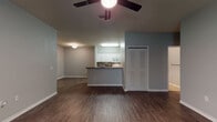 This single-story residence offers a well-organized layout that connects the main living area to a functional kitchen via an open-concept design. The living area features dark hardwood-style flooring and a ceiling fan overhead, creating a comfortable and practical atmosphere. A louvered closet door provides convenient storage near the living space.

The kitchen is positioned just off the living area and is equipped with white cabinetry, granite-toned countertops, a tile backsplash, white appliances including an electric range and over-the-range microwave, and light tile flooring. A peninsula with a built-in sink and matching countertop serves as a natural divider between the kitchen and living spaces.

Two bedrooms are finished with neutral-toned carpet and feature windows fitted with blinds that allow for natural light. One bedroom includes direct access to a bathroom and benefits from additional closet space. Both bathrooms are similarly appointed, each featuring white vanity cabinetry, granite-toned countertops, a large mirror with a multi-bulb light fixture above, and light tile flooring. The overall color palette throughout the unit consists of soft gray-blue tones on the walls, complemented by white trim and clean finishes.