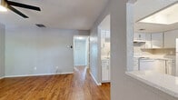 Located at 8400 49th St N in Pinellas Park, Florida, this two-bedroom, one-bathroom single-floor home offers a practical and well-organized layout. Warm wood-look flooring flows throughout the main living areas, complemented by neutral gray walls and textured ceilings that lend a consistent, cohesive aesthetic.

The combined kitchen and living area serves as the heart of the home. The kitchen is equipped with white shaker-style cabinetry, light stone countertops, a tile backsplash, a stainless steel sink, and white appliances including a range and refrigerator. A window allows natural light to brighten the space.

The primary bedroom features wood-look flooring, a ceiling fan with light fixture, and a window for natural light. The second bedroom is finished with plush carpet and also includes a window, providing a comfortable and quiet retreat. A dedicated closet and hallway offer additional storage and connectivity throughout the unit.

The bathroom is clean and functional, outfitted with a white vanity with stone-style countertop, a large mirror with overhead lighting, and a full tub-shower combination. Wood-look flooring ties the bathroom to the rest of the home's design. Overall, the space presents a tidy, move-in ready home with consistent finishes throughout.