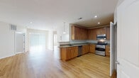 This single-floor residence offers a thoughtfully designed open-concept layout that seamlessly connects the main living areas. Warm-toned hardwood flooring runs consistently throughout the space, creating a cohesive and inviting atmosphere.

The kitchen is a standout feature, outfitted with rich medium-toned wood cabinetry offering generous storage, granite countertops with speckled detailing, and a full suite of stainless steel appliances including a gas range, built-in microwave, dishwasher, and refrigerator. A peninsula with pendant lighting provides additional prep space and connects the kitchen to the open living area. An in-unit washer and dryer are also accessible from the kitchen.

The living and dining areas are generously proportioned, bathed in natural light from large windows dressed with blinds, and illuminated by recessed ceiling lighting. The clean white walls and neutral palette contribute to a bright, airy feel throughout.

The bedrooms feature the same hardwood flooring and neutral tones, with windows that allow natural light to filter in. The bathrooms are finished with light tile flooring, white cabinetry with granite countertops, and oval mirrors. One bathroom includes a full tub-shower combination with tiled surround, while another offers a more compact configuration with a vanity and toilet.