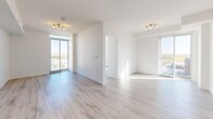 This bright and contemporary 3-bedroom, 2-bathroom unit offers a clean, modern aesthetic defined by crisp white walls, light-toned hardwood-style flooring, and an abundance of natural light. The open-concept living and kitchen area forms the heart of the unit, where a well-appointed kitchen features white shaker-style cabinetry, a white countertop peninsula, a classic subway tile backsplash, and a full suite of stainless steel appliances including a refrigerator, electric range, microwave, and dishwasher. Track lighting overhead enhances the kitchen's functionality. The adjacent living area is generously proportioned, benefiting from floor-to-ceiling windows that frame elevated cityscape and treetop views, flooding the space with natural light. Each of the three bedrooms continues the light and airy theme, with large sliding glass doors or floor-to-ceiling windows offering sweeping outdoor views. Bedrooms include sliding-door closets for practical storage. The two bathrooms are finished with neutral tile flooring; one features a glass-enclosed shower with a vanity and mirror, while the other includes a soaker tub with white tile surround. A staircase is also present within the unit, adding to the versatility of the layout. Throughout, the design emphasizes a clean, minimalist style with consistent finishes.