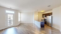 Located at 527 Old Bridge Turnpike in East Brunswick, NJ, this well-appointed two-bedroom, one-bathroom residence offers a thoughtfully designed single-floor layout. The open-concept living and kitchen area serves as the heart of the home, where durable hardwood-style flooring flows seamlessly throughout. The kitchen is a standout feature, equipped with dark espresso cabinetry, granite countertops, a center island with a built-in sink, stainless steel appliances including a refrigerator, electric range, and microwave, and stylish pendant lighting overhead. The living area benefits from natural light streaming through a glass door that opens to a private balcony, accompanied by an additional window that further brightens the space. The spacious primary bedroom provides a generous retreat with plush carpeting and closet access, while the second bedroom features hardwood-style flooring and a clean, neutral palette. The bathroom is finished with a granite-topped dark vanity, a large mirror, tile flooring, and accessible grab bars. Throughout the residence, crisp white walls, clean trim, and modern finishes create a cohesive and contemporary ambiance.