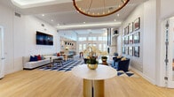 Located at 401 Janes Ave in Bolingbrook, IL, this single-floor community clubhouse offers a generously sized, thoughtfully designed space that blends sophistication with functionality. The grand main living area welcomes visitors with soaring ceilings, warm hardwood flooring, and a bold blue-and-white geometric area rug. A striking circular chandelier anchors the room, while large windows flood the space with natural light. Curated artwork and elegant furnishings in a navy, gold, and white palette lend a polished, upscale ambiance throughout.

The dining areas provide intimate settings for gatherings, one featuring dramatic navy textured walls, a sculptural pendant light, and views of the surrounding greenery. A sun-drenched lounge nook with floor-to-ceiling windows, gold-striped accent walls, and built-in shelving offers a bright, inviting retreat.

Three well-appointed offices are outfitted with modern workstations, lounge seating, and French doors that connect seamlessly to the main common areas. The dual entrances are clean and welcoming, with patterned rugs and glass-paneled doors.

A standout fitness center rounds out the facility, equipped with free weights, cable machines, a Smith machine, and motivational wall graphics, all set beneath high striped ceilings with ample room to train.