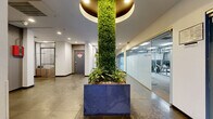 Located at 5555 Harold Way in Los Angeles, this fitness center and entrance lobby offers a thoughtfully designed amenity space. The entrance immediately impresses with its polished large-format stone tile flooring, recessed lighting, and a dramatic living green column wrapped in lush foliage and anchored by a sculptural planter — a standout biophilic design element that sets a fresh, modern tone. Full-length mirrors and potted tropical plants accent the lobby, creating an open and welcoming atmosphere.

Adjacent to the entrance, the fitness center is accessed through frosted glass doors clearly labeled "Fitness Center," maintaining visual connectivity while providing a defined workout environment. The gym features carpet tile flooring, bright overhead panel lighting, and mirror-lined walls that enhance the sense of space. Equipment includes treadmills, cable machines, a multi-use weight rack, an adjustable bench, barbells, dumbbells, medicine balls, and cycling equipment — offering a comprehensive range of cardio and strength training options. The neutral gray color palette throughout the gym contributes to a focused, professional atmosphere. Together, these spaces provide residents with a polished and functional amenity experience in the heart of Hollywood.