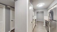 Located at 1421 N University Ave in Little Rock, Arkansas, this single-story unit presents a clean, modern aesthetic defined by a neutral gray color palette, white trim, and a combination of wood-style laminate flooring and plush carpeting throughout.

The open living area is a standout feature, offering wood-style flooring and a large sliding glass door fitted with vertical blinds that opens onto a private balcony overlooking mature trees. Natural light filters generously into the space, enhancing its airy feel. An additional carpeted living or sitting area includes a ceiling fan with light fixture and a wide window framing outdoor greenery.

The galley-style kitchen is well-appointed with white shaker cabinetry, granite-look countertops, a stainless steel sink, and black stainless appliances including a range, microwave, refrigerator, and dishwasher. Wood-style flooring continues throughout this space for easy maintenance.

The bedrooms are carpeted and generously sized, each featuring ample closet space — including walk-in and built-in shelved closets — along with ceiling fans. The bathrooms are finished with granite-topped vanities, wood-style flooring, and a tiled tub-shower combination, maintaining the unit's consistent, updated character.