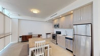Located at 8155 Van Nuys Blvd in Panorama City, Los Angeles, this well-appointed one-bedroom, one-bathroom residence offers a thoughtfully designed single-floor layout with modern finishes throughout. The open-concept living area seamlessly connects the kitchen, dining, and living spaces, creating an efficient and inviting flow. The kitchen is outfitted with light wood cabinetry, stainless steel appliances including a refrigerator, electric range, microwave, and dishwasher, complemented by clean white countertops and recessed lighting overhead. The living area benefits from floor-to-ceiling windows dressed with roller shades, allowing abundant natural light while offering privacy and views of the surrounding neighborhood. The bedroom continues the modern aesthetic, featuring the same expansive windows, a built-in wardrobe with ample storage, and a sleek wall-mounted HVAC unit. The bathroom is finished with classic white subway tile surrounding a soaking tub and shower combination enclosed by a glass door, paired with chrome fixtures for a clean, contemporary look. Light-toned flooring, crisp white walls, and warm wood-accented doors and trim tie the entire space together into a cohesive, minimalist design.