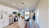 Located on West Colfax Avenue in Denver, Colorado, this well-appointed one-bedroom, one-bathroom unit offers a thoughtfully designed open-concept layout with modern finishes throughout. Light wood-tone flooring flows seamlessly across the main living area, connecting the kitchen, dining, and living spaces into one cohesive, functional zone.

The kitchen is a standout feature, outfitted with crisp white shaker cabinetry, a subway tile backsplash, stainless steel appliances including a refrigerator, range, microwave, and dishwasher, and a central island with a white quartz countertop and bar seating beneath stylish pendant lighting. A full-size front entry door with a modern matte black finish anchors the entryway.

The living room is bright and airy, anchored by a large sliding glass door that opens to a private balcony offering views of the Denver skyline. Natural light fills the space throughout the day, enhancing the clean, contemporary aesthetic.

The bedroom features plush carpet flooring, a ceiling fan, and a large window framing additional city views. A dedicated closet provides ample storage. The bathroom includes a white subway-tiled tub and shower combo, a single-sink vanity with white cabinetry, and wood-tone flooring that maintains the cohesive design language found throughout the unit.