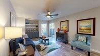 This single-floor residence offers a thoughtfully designed layout that balances comfort and functionality throughout. The living room serves as the heart of the home, featuring wood-style flooring, a ceiling fan, and a textured ceiling. Built-in shelving with lower cabinetry lines one wall, providing ample display and storage space, while sliding glass doors open to an outdoor area, filling the room with natural light and greenery views. The adjacent dining area flows seamlessly into the kitchen, which is equipped with gray cabinetry, granite countertops, a tile backsplash, stainless steel appliances including a built-in microwave and range, and a black refrigerator. A peninsula breakfast bar separates the two spaces with ease. The two bedrooms are carpeted and each feature ceiling fans, windows with outdoor views, and a calm, neutral palette that promotes rest. The full bathroom includes a shower-tub combination, gray vanity cabinetry with a light countertop, and wood-style tile flooring. A dedicated in-unit laundry area houses a full-size side-by-side washer and dryer, adding everyday convenience. Throughout the residence, consistent wood-style flooring, neutral wall tones, and an efficient single-level floor plan create a cohesive and comfortable living environment.