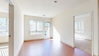 This single-story residence features three bedrooms, two bathrooms, and a thoughtfully arranged floor plan that maximizes every square foot. The open-concept kitchen anchors the living area and is outfitted with warm wood cabinetry, a peninsula with a dark countertop, a full suite of white appliances including a dishwasher, range, and microwave, and recessed lighting overhead. Rich wood-tone flooring runs throughout the main living and kitchen areas, lending warmth to the bright, neutral-toned interior. The living room is bathed in natural light from large windows fitted with vertical blinds, with direct access to an outdoor area through a glass door. The bedrooms are carpeted and well-lit, each featuring windows that invite natural light. The primary bedroom offers a comfortable footprint and connects to a dedicated closet with adjustable shelving systems for versatile storage. The two bathrooms are finished with tile flooring and warm wood cabinetry; one features a shower-tub combo and wall-mounted storage, while the other includes a stand-alone shower, a vanity with a light countertop, and additional overhead cabinetry. The overall design is clean, functional, and move-in ready, with a consistent neutral palette throughout.