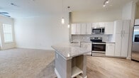 Located at 2920 W El Dorado in Friendswood, TX, this single-floor residence offers a thoughtfully designed layout with modern finishes throughout. The kitchen serves as the centerpiece of the home, showcasing a granite-topped island with seating, crisp white cabinetry, a subway tile backsplash, and a full suite of stainless steel appliances including a French door refrigerator, electric range, and built-in microwave. Pendant lighting and track lighting illuminate the space, while wood-look flooring grounds the area with warmth and durability. The kitchen flows seamlessly into the open living area, which features plush neutral carpeting and a ceiling fan. A glass-paneled exterior door allows natural light to pour in and provides access to the outdoors. The bedrooms continue the soft carpeted flooring and are bathed in natural light through sizable windows with blinds, offering a calm and comfortable retreat. The bathroom is well-finished with granite-topped cabinetry, wood-look flooring, and a glass-enclosed walk-in shower with tile surround. Additional built-in closet storage is present throughout, enhancing the overall functionality of this clean, contemporary residence.