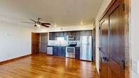 This single-floor unit combines modern finishes with warm, natural materials to create a cohesive and comfortable living space. Rich hardwood flooring flows throughout, complemented by solid wood doors and trim that lend a sense of craftsmanship to every room.

The open kitchen is a standout feature, outfitted with dark cabinetry, granite countertops, and a full suite of stainless steel appliances including a refrigerator, range, over-the-range microwave, and dishwasher. Recessed lighting and a ceiling fan enhance the functionality of the space.

The living area is generously proportioned, bathed in natural light through wood-trimmed windows that frame views of the surrounding neighborhood. A ceiling fan adds comfort, while the gleaming hardwood floors give the room an open, airy quality.

The bedrooms continue the warm aesthetic, each featuring hardwood floors, ceiling fans, natural light, and access to closet space. One bedroom includes a walk-in closet, providing practical storage.

The bathrooms offer clean, bright finishes. One includes a full soaking tub with a tub-surround, while the other features a standalone glass-door shower with a vanity and framed mirror. Together, these spaces round out a well-designed, move-in ready unit with consistent style throughout.
