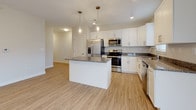 Located at 243 Talcottville Rd in Vernon Rockville, Connecticut, this single-floor residence offers a thoughtfully designed layout with clean, contemporary finishes throughout. The kitchen serves as a central highlight, featuring crisp white shaker cabinetry, dark granite countertops, stainless steel appliances including a refrigerator with ice maker, range, microwave, and dishwasher, along with a central island topped with matching granite and illuminated by elegant pendant lighting. Light wood-style flooring flows through the kitchen and living areas, lending warmth and continuity to the open layout. Natural light enters through multiple windows, including a sliding glass door that connects the living space to the outdoors. The bedrooms are finished with plush wall-to-wall carpeting and neutral wall tones, creating comfortable, versatile spaces. Two bathrooms serve the unit: one features a walk-in shower stall with built-in shelving and a dark-cabinetry vanity with a white countertop, while the second offers a full soaking tub and shower combination with a matching vanity setup. Both bathrooms include light wood-style flooring and clean white fixtures. The overall aesthetic is modern and move-in ready, with a neutral palette that provides a welcoming and functional living environment.