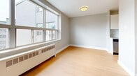 Located at 746 Midland Ave in Toronto's Scarborough neighbourhood, this one-bedroom, one-bathroom unit offers a practical and efficiently designed single-floor layout. The interior features warm light hardwood flooring throughout, complemented by soft grey-toned walls and clean white baseboards that create a bright, neutral palette.

The open living area provides a comfortable amount of space for everyday living and connects to a compact kitchen nook, which includes cabinetry and stainless steel appliances tucked neatly behind a partial dividing wall. A hallway links the main living spaces to the private areas of the unit.

The bedroom is a well-proportioned room featuring a large sliding double-door closet for ample storage. Natural light filters in through a sizable window fitted with a radiator beneath it, offering views of the surrounding neighbourhood. The room is finished with the same hardwood flooring found throughout the unit.

The bathroom is clean and functional, featuring light tile flooring, white subway tile surrounding a full bathtub and shower combination, a vanity with a wall-mounted mirror, and a toilet — all finished in a crisp, all-white scheme.

Overall, the unit presents a tidy, move-in ready space with consistent finishes and a practical layout well-suited for a single occupant or couple.