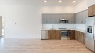 Located at 1517 H Street in Sacramento, CA, this thoughtfully designed two-bedroom, two-bathroom residence offers a modern living experience across a single well-organized floor. The open-concept kitchen is a standout feature, showcasing a sleek combination of gray upper cabinetry and warm wood-toned lower cabinets, light quartz countertops, and a full suite of stainless steel appliances including a side-by-side refrigerator with ice maker, electric range, built-in microwave, and dishwasher. Light wood-style luxury vinyl flooring runs throughout the main living and kitchen areas, lending a clean, contemporary feel. Both bedrooms are carpeted and filled with natural light, each featuring large sliding glass doors that frame views of the tree-lined streetscape outside. Each bedroom is served by its own dedicated closet for convenient storage. The two bathrooms continue the modern aesthetic, featuring warm wood vanities with white countertops, large mirrors with contemporary lighting, and wood-look flooring. One bathroom includes a tub-shower combination with marble-style tile surround. Clean white walls and recessed lighting throughout create a bright, airy ambiance that complements the building's contemporary urban character.