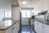 Located at 295 Dufferin St in Toronto's vibrant Dufferin Grove neighbourhood, this thoughtfully laid-out 3-bedroom, 2-bathroom unit offers a efficient and functional single-floor living space. The open-concept design connects the living area to a well-appointed kitchen, which features white cabinetry, dark subway tile backsplash, dark countertops, stainless steel appliances including a stove, dishwasher, and microwave, and a window overlooking the surrounding cityscape. A peninsula counter extends into the living area, creating a natural divide while maintaining an open feel. Wood-look laminate flooring runs throughout the main living and bedroom areas, providing a warm and cohesive aesthetic. The three bedrooms are bright and versatile, with neutral warm-beige walls and windows that bring in natural light. The primary bedroom includes mirrored sliding closet doors, maximizing both storage and the sense of space. The two bathrooms are finished with clean, contemporary fixtures; one features classic white subway tile surrounding a full bathtub, while the other includes a stone-look vanity countertop and tile flooring. Textured ceilings and crisp white trim complete the unit's clean, modern character throughout.