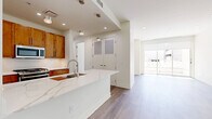 Located at 5355 E High St in Phoenix, AZ, this well-appointed 2-bedroom, 2-bathroom residence offers a thoughtfully designed single-level layout. The open-concept kitchen and living area serves as the heart of the home, anchored by a striking waterfall quartz island with an undermount sink and stylish pendant lighting. Warm wood cabinetry, white quartz countertops, and a full suite of stainless steel appliances — including a gas range, built-in microwave, and refrigerator — complete the kitchen. Wide-plank wood-look flooring flows consistently throughout the space, lending a cohesive, contemporary aesthetic. The living area opens directly to an outdoor patio through floor-to-ceiling sliding glass doors, filling the space with natural light. The spacious primary bedroom also enjoys outdoor patio access and connects to a generously sized en-suite bathroom featuring a dual-sink vanity with wood cabinetry, a freestanding soaking tub, and a separate walk-in closet with multi-tier shelving. The second bedroom is bright and well-proportioned, served by a full bathroom with a tub/shower combo and matching wood vanity. Three closets across the unit provide ample storage throughout.