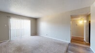This single-story space is thoughtfully laid out to maximize functionality across its key living areas. The main living room is generously sized, featuring neutral-toned carpet, textured walls, and a popcorn ceiling. Vertical blinds cover a large sliding glass door that provides access to an outdoor area and allows natural light to filter into the room. The space transitions to wood-look flooring toward the entryway, where a ceiling fan with integrated lighting adds practical comfort.

The kitchen is efficiently designed in a galley-style configuration, featuring speckled laminate countertops, an electric range, and a dishwasher. Wood-look flooring carries through this area, complementing the neutral wall tones.

The bedroom is a comfortable, well-proportioned space with plush carpet, a ceiling fan with light fixture, and a window fitted with horizontal blinds that bring in natural light. A dedicated walk-in closet with built-in shelving provides ample storage, while a separate doorway leads directly to the bathroom.

The bathroom features a tiled tub-and-shower combination accented with a decorative mosaic border, a speckled vanity countertop, and wood-look flooring, completing the space with a clean, cohesive aesthetic throughout.