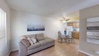 This single-floor unit offers an efficient and well-organized layout across a compact footprint, accommodating a living room, dining room, kitchen, bedroom, bathroom, office, and two closets. The interior is characterized by painted concrete block walls throughout, hardwood-style flooring, and textured ceilings, lending the space a consistent, utilitarian aesthetic.

The open-concept living and dining area forms the heart of the unit. The living space provides room for comfortable seating, while the adjacent dining area features a ceiling fan with light fixture overhead. The kitchen is positioned nearby, equipped with warm oak cabinetry, granite-look countertops, a white electric range, and a full-size refrigerator, all complemented by a tiled backsplash.

The bedroom receives natural light through a window with blinds and offers enough space for a standard bed. A separate office provides additional flexibility, also benefiting from a window. The bathroom includes a wood-toned vanity with granite-style countertop and a combined shower and toilet area. Two closets offer practical storage throughout the unit.