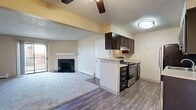 This 750-square-foot, two-bedroom, two-bathroom apartment offers a functional single-story layout. The living room features a black-surround fireplace, sliding glass doors to a private balcony, and carpet flooring with baseboard heating. The kitchen includes dark cabinetry, stainless steel appliances, a dishwasher, and wood-style flooring that extends into the dining area. Both bedrooms are carpeted and include louvered bi-fold closets, with the 170-square-foot primary bedroom offering additional space. The bathrooms feature dark vanity cabinetry with light countertops and wood-style flooring, with one bath including a full soaking tub. Textured ceilings are consistent throughout the unit.