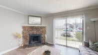 This single-floor, one-bedroom, one-bathroom residence offers a thoughtfully arranged layout that maximizes every square foot of its compact footprint. The living room serves as the centerpiece of the home, highlighted by a striking floor-to-ceiling stone fireplace with a classic white mantle and slate hearth. Large sliding glass doors with vertical blinds flood the space with natural light while providing views of the surrounding neighborhood. Durable wood-look flooring extends throughout the living and dining areas, adding warmth and continuity.

The open-concept kitchen features gray cabinetry, granite-style countertops, and a peninsula that seamlessly connects to the combined dining and living area. Black appliances, including a range and refrigerator, complete the functional kitchen setup. The adjacent dining area provides a dedicated space for meals.

The bedroom offers a carpeted retreat with a window that brings in natural light, while the walk-in closet provides generous storage with built-in shelving and hanging rods on multiple walls. The bathroom includes a granite-topped vanity with gray cabinetry and a large mirror, maintaining the home's consistent neutral aesthetic throughout.