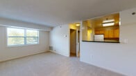 This single-floor residence offers a practical and comfortable layout designed to maximize livable space. The open-concept living area is bright and welcoming, featuring plush wall-to-wall carpeting, a textured ceiling, and a window that invites natural light and outdoor views. A half-wall partition seamlessly connects the living space to the kitchen, which is well-equipped with warm honey-toned wood cabinetry, dark granite-style countertops, white appliances including a refrigerator, electric range, built-in microwave, and dishwasher, as well as tile flooring and a skylight panel overhead for added brightness.

The bedrooms are generously sized, each carpeted and featuring ceiling fans with light fixtures. One bedroom includes access to a closet and an adjoining bathroom, while additional doors provide further storage or hallway access. The neutral wall tones throughout create a clean, move-in-ready atmosphere.

Two full bathrooms serve the residence. One features a walk-in shower stall with chrome fixtures and tile flooring, while the other offers a full soaking tub with a shower curtain rod, a vanity, and matching tile floors. Both bathrooms are finished in light, neutral tones. Overall, the space presents a functional and cohesive design suited for comfortable everyday living.