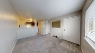 Located at 2102 E 51st St S in Tulsa, Oklahoma, this one-bedroom, one-bathroom unit offers a practical and efficient single-floor layout. The combined living, dining, and kitchen area forms the heart of the space, featuring soft carpet flooring in the living and dining zones and wood-look vinyl flooring near the entryway. A distinctive white diagonal-paneled half-wall divides the living area from the kitchen, which is equipped with dark wood cabinetry, an under-cabinet range hood, and overhead lighting. The textured popcorn ceilings are consistent throughout the unit, lending a classic character to each room. The bedroom is a cozy, carpeted retreat with a window that invites natural light and provides an open pass-through view to the living area, enhancing the sense of connectivity. It also offers direct access to the bathroom. The bathroom features wood-look vinyl flooring, a dark wood vanity, a full tub-shower combination with white tile surround, and clean white fixtures. Two closets provide ample storage for the space. Neutral wall tones throughout create a calm, cohesive atmosphere well-suited for comfortable everyday living.