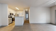 This single-story residence offers three bedrooms, two bathrooms, and a thoughtfully arranged floor plan across a comfortably sized footprint. The open-concept kitchen and living area serves as the heart of the home, featuring wood-look luxury vinyl plank flooring, a peninsula with light quartz countertops, and a full suite of stainless steel appliances including an electric range, built-in microwave, dishwasher, and refrigerator. Gray shaker-style cabinetry lines both sides of the galley-style kitchen, providing ample storage throughout.

The living area is bright and open, with neutral white walls and easy access to the entry door. Bedrooms are carpeted for comfort, with ceiling fans and windows that allow natural light. The primary bedroom includes a spacious walk-in closet with dual wire shelving systems, while secondary bedrooms feature standard closets with hanging rods.

Both bathrooms are finished with gray vanity cabinetry, quartz countertops, and wood-look tile flooring. The full bathroom includes an extended vanity with a large mirror. A dedicated laundry area and consistent neutral finishes throughout give this residence a clean, move-in ready appeal.