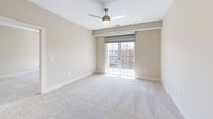Located at 11335 N Michigan Rd in Carmel, Indiana, this well-appointed 2-bedroom, 2-bathroom unit offers a thoughtfully designed single-level layout. The kitchen serves as a centerpiece, featuring white shaker cabinetry, a subway tile backsplash, sleek white quartz countertops, stainless steel appliances, and a central island with pendant lighting overhead — all set atop warm hardwood-style flooring. Both bathrooms continue the modern aesthetic with grey veined tile surrounds, white vanities, and hardwood-style flooring; one bathroom includes a glass-enclosed walk-in shower, while the second offers a full soaking tub. The spacious primary bedroom includes a ceiling fan, plush carpeting, a walk-in closet with wire shelving, and sliding glass doors opening to a private balcony with outdoor views. The second bedroom is generously sized with dual windows that invite abundant natural light and a ceiling fan for added comfort. A dedicated laundry room with side-by-side washer and dryer adds everyday convenience. Neutral tones, clean lines, and quality finishes throughout give this unit a bright, move-in-ready feel.