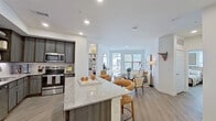 This well-designed single-floor residence showcases a thoughtfully planned open-concept layout connecting the kitchen, dining, and living areas into one cohesive space. The kitchen is a functional highlight, outfitted with dark wood-toned cabinetry, a subway tile backsplash, stainless steel appliances including a range, microwave, and dishwasher, and generous granite countertops that extend to a peninsula with bar seating. Light wood-tone flooring runs throughout, complementing the bright white walls and recessed lighting overhead.

The living and dining area benefits from large windows that draw in natural light and offer outdoor views, creating an open and airy atmosphere. The living room provides a comfortable retreat with clean lines and neutral tones.

Both bedrooms are well-proportioned, each featuring multiple windows with blinds, ceiling fans, and light-filled corners that enhance the sense of space. The bathrooms are finished consistently with granite-topped dark vanities, marble-style large-format tile surrounding the soaking tub and shower combinations, and wood-look flooring, lending a clean, contemporary feel throughout the residence.