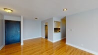 Located at 1037 Des Plaines Ave in Forest Park, IL, this single-floor unit showcases a clean, modern aesthetic throughout. The open living and dining area is anchored by warm hardwood flooring that extends across the space, complemented by soft gray walls and recessed lighting that create a bright, welcoming atmosphere.

The kitchen is accessible via a pass-through window that opens to the living area, offering a connected feel. It features white shaker-style cabinetry, light quartz countertops, a gray subway tile backsplash, and stainless steel appliances including a refrigerator, electric range, and dishwasher. A dedicated dining area sits adjacent to the kitchen.

The bedrooms continue the hardwood flooring and neutral palette, each offering closet storage — one with a double-door closet and another with a built-in closet — providing functional storage solutions. Ceiling fans add to the comfort of the sleeping areas.

The bathroom is finished with large white wall tiles accented by a decorative mosaic border, a wood-framed vanity mirror, and a light countertop with brushed nickel fixtures. The overall design is cohesive and well-maintained, offering a move-in ready living environment.