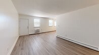 Located at 319 Whites Rd in Lansdale, PA, this 2-bedroom, 1-bathroom unit offers a well-designed single-floor layout that makes efficient use of its space. The open-concept living room and kitchen area is anchored by light-toned luxury vinyl plank flooring and bright white walls, creating a clean and airy atmosphere. Multiple windows along the living area allow natural light to fill the room, complemented by baseboard heating and a wall AC unit.

The kitchen is a standout feature, showcasing rich dark-cherry cabinetry, granite-look countertops, and a full suite of stainless steel appliances including a range, microwave, dishwasher, and refrigerator. A ceiling fan overhead adds to the functional appeal of this well-appointed space.

Both bedrooms are generously sized and finished with plush wall-to-wall carpeting. The primary bedroom includes a closet and offers a comfortable, private retreat. The second bedroom features its own window with outdoor views and a wall-mounted AC unit.

The bathroom is elegantly appointed with large-format marble-patterned tile surrounding a full soaking tub and shower. A private outdoor deck rounds out the unit, offering a peaceful spot surrounded by mature trees and greenery — a rare and refreshing outdoor amenity.