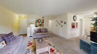 Located at 750 Gaines School Rd in Athens, GA, this single-floor residence offers a practical and comfortable layout across two bedrooms and three bathrooms. The living room features soft carpeting, neutral warm-toned walls, and a sliding glass door that invites natural light and outdoor views, creating an open and welcoming atmosphere. An open passage connects the living area to the dining space, which benefits from a large window overlooking greenery outside. The kitchen is efficiently designed with white cabinetry extending to the upper walls, a stainless steel sink, electric range with overhead ventilation, dishwasher, and refrigerator. A built-in shelving alcove adjacent to the kitchen provides convenient pantry-style storage. Both bedrooms are carpeted and well-proportioned, with the primary bedroom offering generous space, a closet, and a window for natural light. The bathrooms are clean and functional — one features a tub/shower combination with wood-look flooring, while another includes a vanity with under-cabinet storage and lighted mirror. Hardwood-style flooring runs through the kitchen and bathrooms, complementing the carpeted living and sleeping areas throughout the residence.