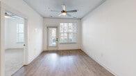 This well-appointed one-bedroom, one-bathroom residence in Greenwood, Indiana offers a smartly utilized single-floor layout with a clean, modern aesthetic throughout. The open-concept kitchen and living room serves as the heart of the home, where warm hardwood-style flooring, crown molding, and a ceiling fan create an inviting atmosphere. A private exterior door and a large window flood the living area with natural light while offering views of the surrounding exterior. The kitchen is a standout feature, boasting white shaker cabinetry, a subway tile backsplash, stainless steel appliances including a refrigerator, range, and microwave, and a generous island with light quartz countertops and pendant lighting above. Ample closet and storage doors adjacent to the kitchen provide convenient organization space. The bedroom is carpeted for comfort, features a ceiling fan, and is brightened by a large window with outdoor views of a pergola and patio area. A dedicated closet offers additional storage. The full bathroom is finished with wood-style flooring, a white vanity with modern hardware, and a tiled tub-shower combination. The overall palette of crisp whites and neutral tones lends the space a fresh, move-in-ready feel.