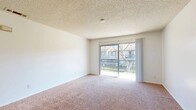Located in Redlands, CA, this one-bedroom, one-bathroom unit offers a well-organized, single-floor layout that makes efficient use of its compact footprint. The living room serves as the heart of the home, featuring plush carpeting, neutral white walls, and a sliding glass door that opens to a private balcony overlooking a landscaped outdoor area — allowing natural light to fill the space. A ceiling fan overhead adds both function and comfort to the transition area leading into the kitchen. The galley-style kitchen is well-appointed with crisp white cabinetry, granite-style countertops, light wood-look flooring, and black appliances including a gas range, dishwasher, and refrigerator, all beneath a skylight-style ceiling fixture. The bedroom offers a comfortable, carpeted retreat with a window dressed with blinds that provides natural light and outdoor views. The bathroom features wood-look tile flooring, a vanity with granite-style countertops, and a full tub-shower combination. A dedicated closet with a hanging rod provides practical storage. A hallway connects the rooms, completing this thoughtfully laid-out residence in Southern California.