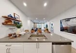 Located at 559 E Arnuado Blvd in Tracy, CA, this single-story home offers three bedrooms and two bathrooms within a well-designed, efficiently arranged floor plan. The interior presents a cohesive modern aesthetic, characterized by crisp white walls, recessed lighting, and wood-style flooring that flows throughout the main living areas.

The kitchen serves as a central hub of the home, featuring white shaker cabinetry extending to the ceiling, stainless steel appliances including a refrigerator, microwave, and range, and a peninsula with a quartz countertop and undermount sink. The peninsula provides seating for multiple bar stools and opens directly to the living and dining area, creating a connected, open-concept space. The living room is equipped with a ceiling fan, large windows for natural light, and access to an exterior door.

The primary bedroom offers a comfortable footprint with a ceiling fan, multiple windows, and plush carpeting. It includes a walk-in closet with built-in shelving. The secondary bedrooms feature carpeted flooring and ample room for varied uses.

Both bathrooms are finished with white cabinetry, quartz countertops, and wood-style flooring. One bathroom features a shower-tub combination, while the other provides a clean, functional layout. Two hallways connect the bedrooms and common areas efficiently throughout the home.