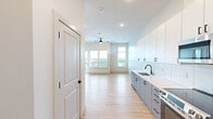 This well-appointed one-bedroom, one-bathroom unit at 212 Durham Ave in Metuchen, NJ offers a thoughtfully designed single-floor layout with a clean, modern aesthetic. Light-toned hardwood flooring flows consistently throughout every room, creating a cohesive and airy feel.

The open kitchen is outfitted with two-tone cabinetry — white upper cabinets paired with gray lower cabinets — complemented by a white subway tile backsplash, light countertops, and a full suite of stainless steel appliances including a range, microwave, dishwasher, and refrigerator. Recessed lighting and black hardware accents complete the contemporary look.

The living room is bright and inviting, featuring a ceiling fan, large windows with blinds, and a glass door that opens to a private balcony with outdoor views of lush greenery. The generously sized primary bedroom benefits from multiple windows that flood the space with natural light, a ceiling fan, and a walk-in closet for ample storage.

The bathroom continues the modern theme with wood-look flooring, a gray vanity with storage drawers, and black hardware accents. An in-unit washer and dryer add everyday convenience. Throughout the unit, clean white walls, panel-style doors with black fixtures, and consistent finishes create a polished, move-in-ready residence.